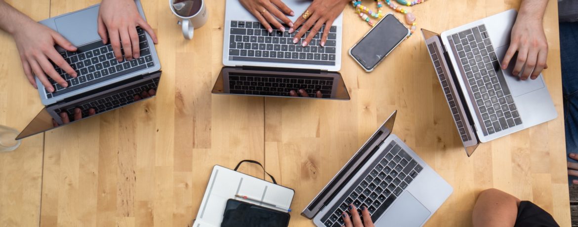 person using macbook pro on brown wooden table